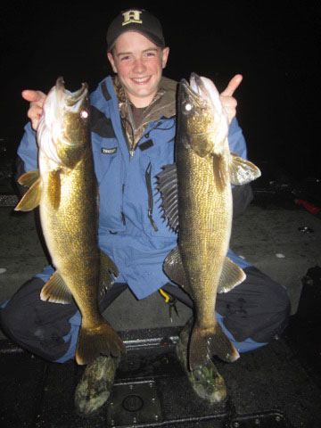 Boy holding up two walleyes fish he caught.